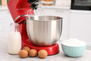 Modern red stand mixer and products on light gray table in kitchen