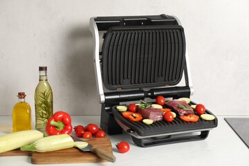 Electric grill and different products on white wooden table