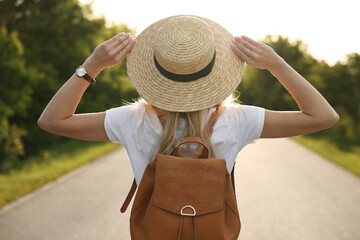 Young woman in straw hat outdoors on spring day, back view