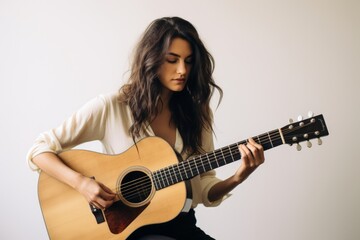 Obraz premium Portrait of a merry woman in her 30s playing the guitar in front of minimalist or empty room background