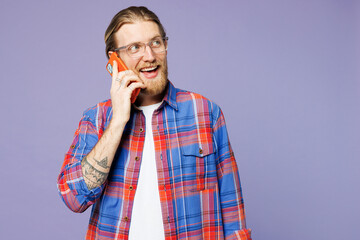 Young smiling happy man he wear blue shirt casual clothes talk speak on mobile cell phone conducting pleasant conversation isolated on plain pastel light purple background studio. Lifestyle concept.