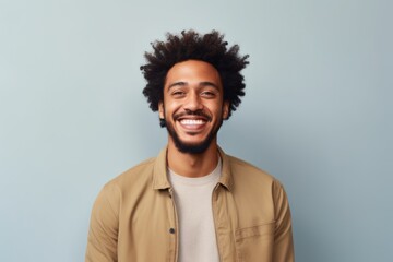 Fototapeta premium Portrait of a joyful afro-american man in his 30s smiling at the camera in minimalist or empty room background