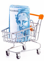 market cart with isolated white background, shopping basket, with large banknote of 100 reais from brazil inside.