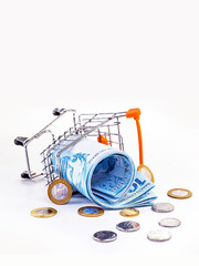 shopping cart falling to the floor, with Brazilian supermarket money. Concept of loss, loss, rising...