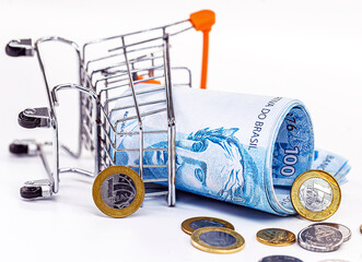 supermarket shopping cart falling to the floor, with Brazilian money. Concept of loss, loss,...