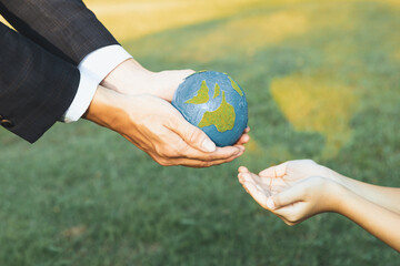 Businessman hand giving Earth globe to little boy as Earth day concept as corporate social...