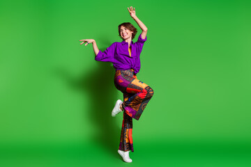Photo of young woman in purple stylish shirt trendy vintage pants and brown bob haircut dancing at nightclub isolated on green color background