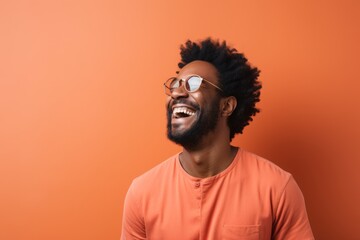 Obraz premium Portrait of a merry afro-american man in his 30s laughing on minimalist or empty room background