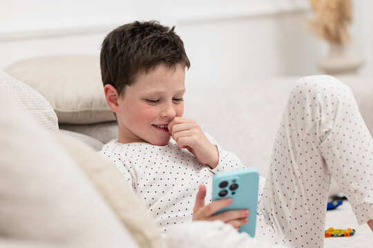 Boy relaxing at home using smartphone