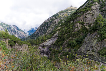 Scenic landscape from hiking trail with aerial view of mountain pass road of Swiss Grimsel pass on a cloudy late summer day. Photo taken September 19th, 2023, Grimsel, Mountain Pass, Switzerland.