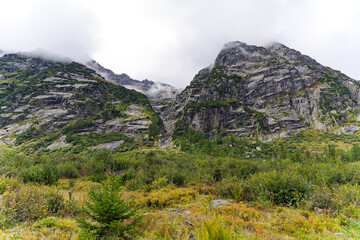 Obraz premium Alpine landscape in the Swiss Alps with fog and peak at mountain pass Grimsel on a cloudy late summer day. Photo taken September 19th, 2023, Grimsel, Canton Bern, Switzerland.
