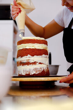 Baker applying cream frosting to layered cake