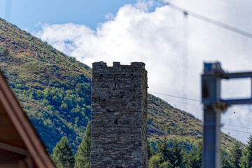 Looking up medieval stone tower of ruins of castle at railway station of Swiss mountain village of...