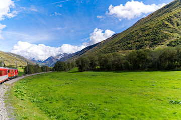 Scenic landscape at Urseren Valley on a sunny late summer day with meadows and mountain panorama seen from narrow gauge railway train. Photo taken September 19th, 2023, Andermatt, Switzerland.