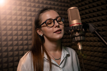 Cute girl in recording studio with mic over acoustic absorber panel background
