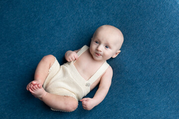 a small child lies on a blue background. newborn boy in pants. baby's first photo shoot
