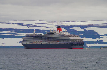 Luxury ocean liner cruise ship cruiseship Victoria anchoring in bay with Iceland glacier mountains...