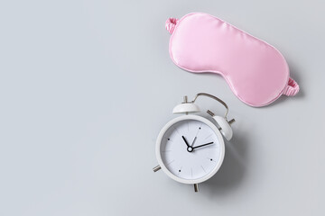 Pink sleeping mask and watch, alarm on gray background. Concept of sleep, health care, daily...