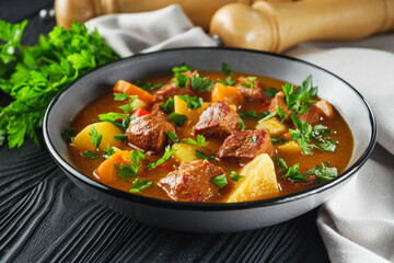 fragrant thick goulash soup on a black wooden rustic background