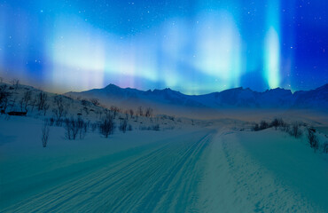 Beautiful winter landscape with snow and ice covered road - Northern lights (Aurora borealis) in...