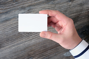 Close-up of a man's hand holding a white plastic bank card.