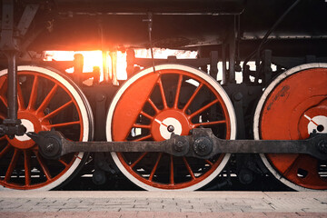 Close-up of a steam locomotive wheel at a railway station.