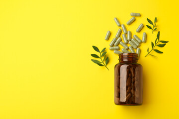 Vitamin pills, branches and bottle on yellow background, flat lay. Space for text