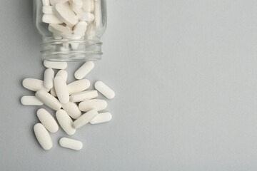 Vitamin pills and bottle on grey background, top view. Space for text