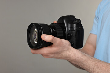 Photographer holding camera on grey background, closeup