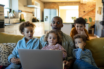 Happy diverse family enjoying time together with laptop at home