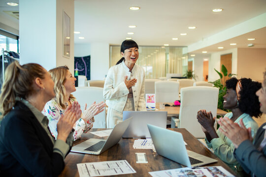 Successful businesswoman receiving applause from colleagues during a meeting in modern office