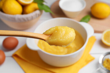 Taking delicious lemon curd from bowl at table, closeup