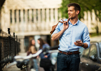 Smiling businessman using smartphone while leaning on bicycle in urban setting