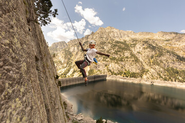 Obraz premium A woman is jumping off a cliff into a lake