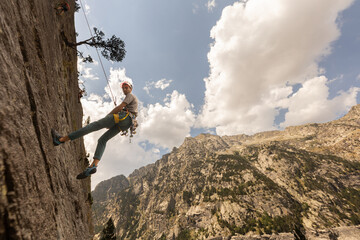 A man is climbing a rock wall with a rope