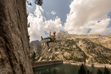 A man is hanging from a rope on a cliff