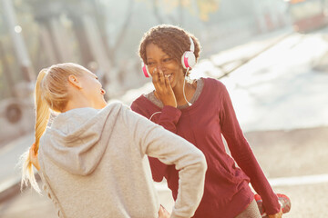Happy diverse female lesbian couple laughing together during outdoor workout in city