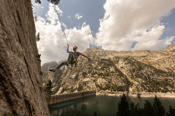 A man is hanging from a rock face with a rope