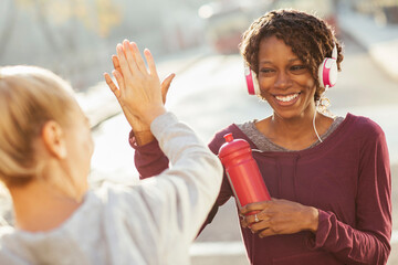 Happy young diverse lesbian couple high fiving during outdoor exercise