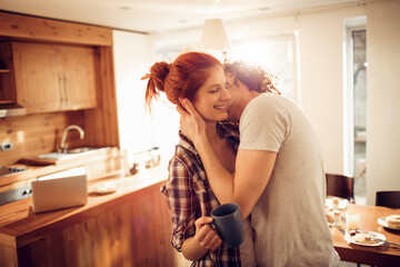Romantic couple kissing in cozy home kitchen