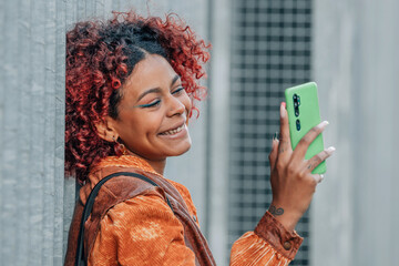 portrait african american woman with mobile phone on the street outdoors