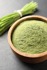 Wheat grass powder in bowl on grey table, closeup