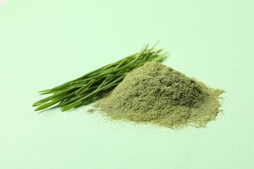 Pile of wheat grass powder and fresh sprouts on green table, closeup