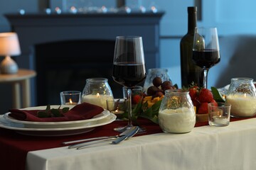 Stylish table setting with burning candles and wine indoors. Romantic dinner