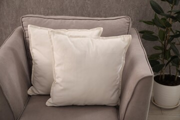 Soft pillows on grey armchair in room