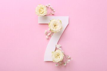 Paper number 7 and beautiful flowers on pink background, top view