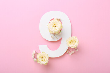 Paper number 9 and beautiful flowers on pink background, top view