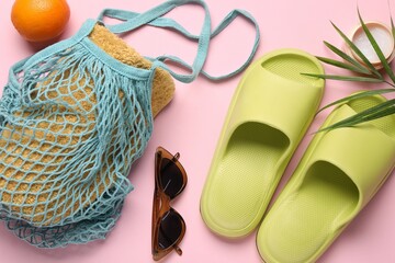 String bag with towel, sunglasses, orange, slippers, cream and palm leaf on pink background, flat...