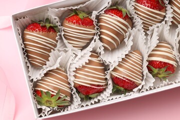 Box with delicious chocolate covered strawberries on pink background, top view
