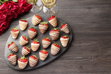 Delicious chocolate covered strawberries, sparkling wine and flowers on wooden table, flat lay....